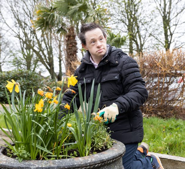 Man kneeling at a flower pot doing some gardening