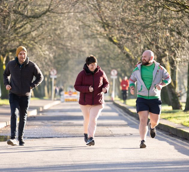 Three people running together in a park